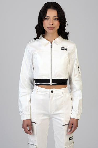 woman in white cropped jacket with a silver zipper, black waistband, and chest patch, paired with white cargo pants with