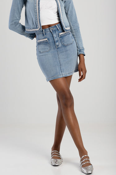 woman wearing a light blue denim mini skirt with braided pocket trim, matching cropped jacket and silver flats