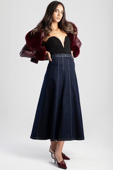 woman wearing a dark indigo denim midi skirt with belt loops and topstitching, paired with a black sweetheart bodice and