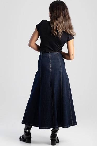 back view of a model wearing a dark denim long skirt with a high waist and visible seams, paired with a black top.