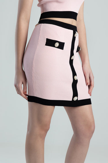 pink ribbed knit skirt with black trim, pearl button accents and a slim belt detail