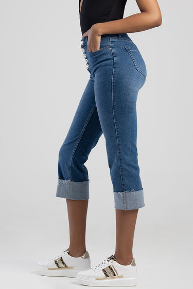 model wearing blue jean traders jeans with a high waist, button front details, rolled cuffs, and white glitter sneakers