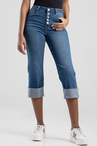 woman wearing high-waisted blue denim jeans with a five button fly and rolled cuffs, paired with white sneakers