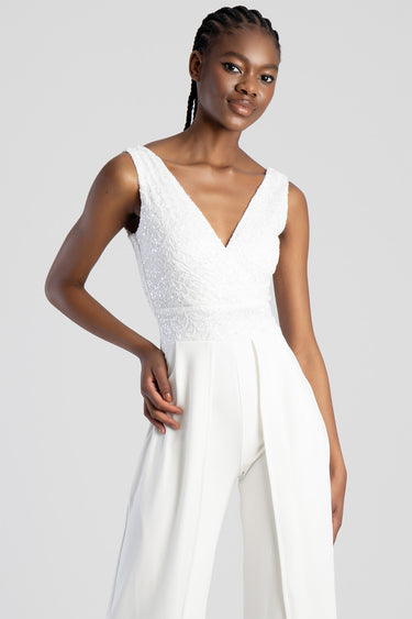 woman wearing a white lace jumpsuit with a deep V neck and wide leg trousers