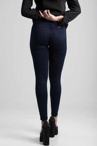 woman from behind wearing dark blue skinny jeans with back pockets and black high heels