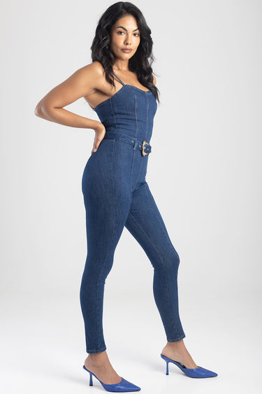 woman in a denim corset jumpsuit with thin straps belted waist and blue pointed toe heels