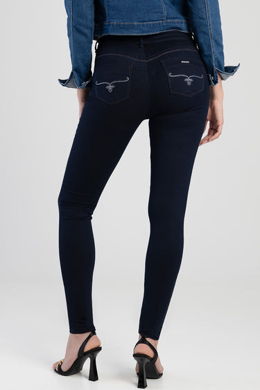 back view of a person in dark blue skinny jeans with rhinestone embellished pockets and heeled sandals