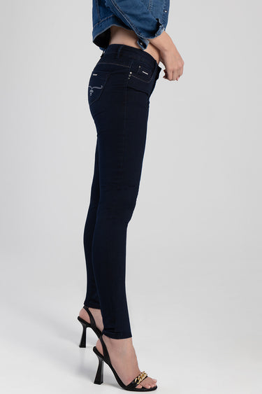side view of a woman wearing dark blue skinny jeans with back pocket embroidery and strappy black heels