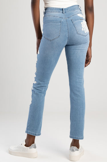 blue denim jeans from the back with floral lace on the right back pocket and lace trim along the outer left leg
