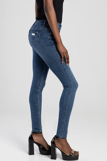 woman wearing blue skinny jeans with back pockets and a small brand patch, paired with a black top and black high heeled