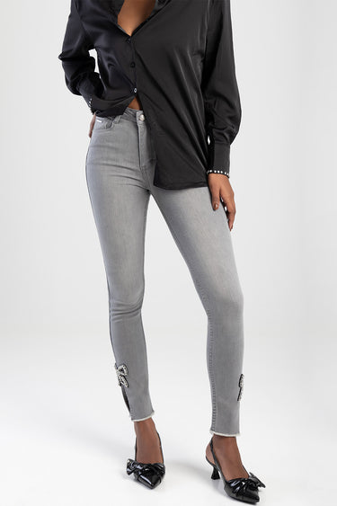 woman in light grey straight jeans with bow accents at the ankles and frayed hems, paired with a black shirt