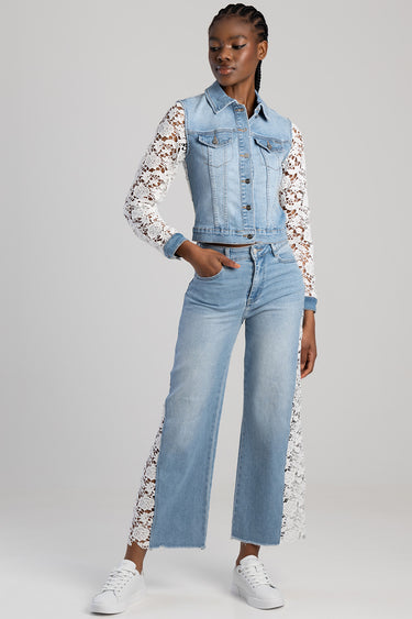 woman in light wash wide leg jeans with white lace side panels, paired with a denim jacket featuring lace sleeves