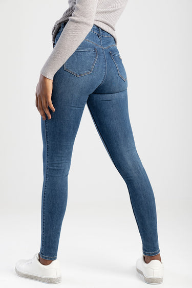 rear view of a woman in blue jean traders skinny jeans with two back pockets and light wash, paired with white sneakers.