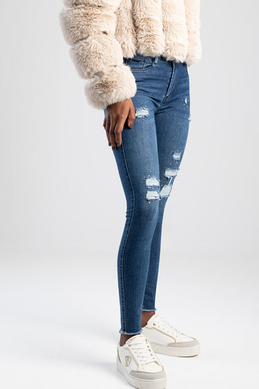 woman wearing blue distressed jeans and white sneakers with a cream fluffy jacket