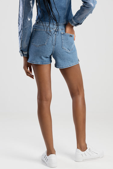 woman wearing light blue denim shorts with back pockets and a matching denim jacket, white sneakers, back view