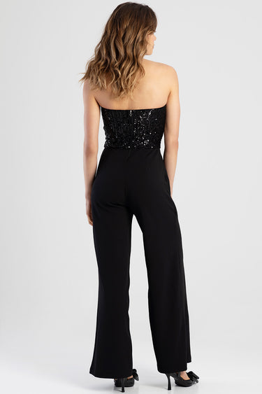back view of woman in a black strapless sequined top and high-waisted wide-leg jumpsuit with a back zipper, wearing black