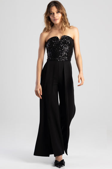 woman wearing a strapless black sequin top with a wide leg black jumpsuit and a relaxed pose