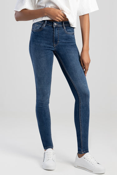 blue skinny jeans on a model wearing a white textured top and white sneakers, front view showing high waist, five pockets