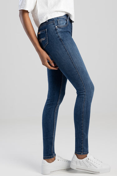 woman in blue skinny jeans with white sneakers, side view showing slim fit and contrast stitching