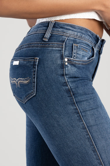 blue denim skinny jeans shown from the side with a back pocket featuring wing embroidery and metal rivets, belt loops and