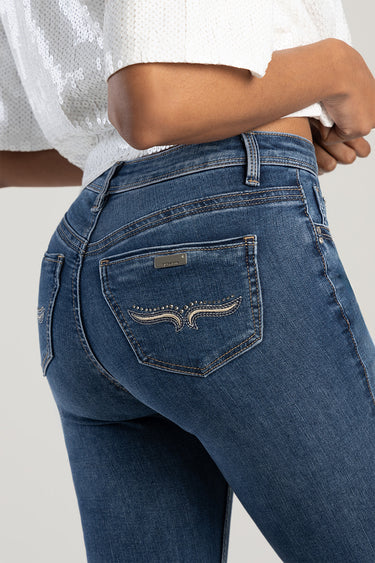 woman wearing blue denim skinny jeans with a stitched wing design on the back pocket and a small metal brand tag