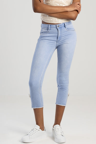 woman in light blue capri jeans with rhinestone accents at the pockets and cropped hems, white sneakers