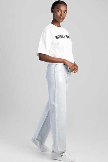 woman wearing a white oversized logo t shirt and light blue wide leg jeans with white sneakers