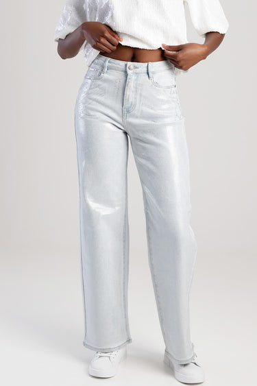woman wearing light blue metallic wide leg jeans with white sneakers and a white cropped top