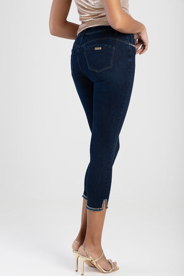 woman wearing dark blue denim capri jeans with back pockets and studded hem details, gold heels.