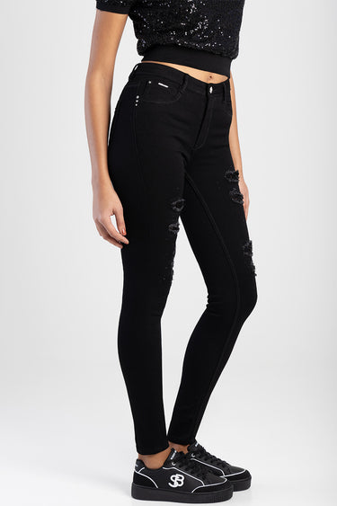 woman wearing distressed black skinny jeans with ripped knees and black sneakers
