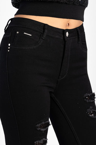 black skinny jeans with torn knees, silver rivets, and a small Blue Jean Traders logo on the front pocket