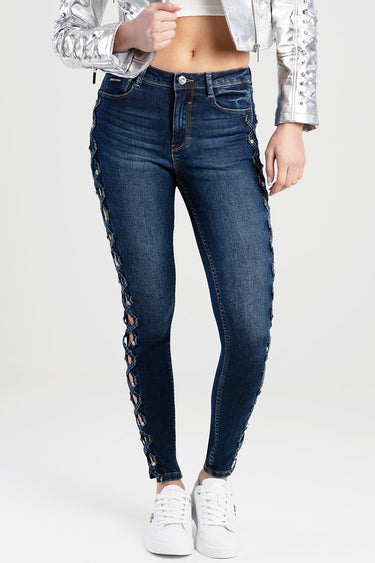 blue skinny jeans with side lace panels and metal eyelets, worn with white sneakers and a silver jacket