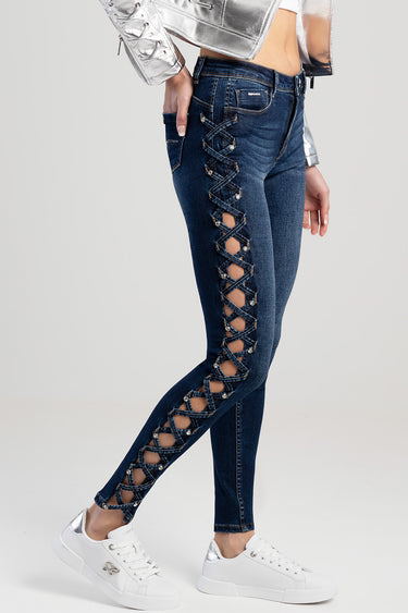 blue skinny jeans with crisscross lace side panels and metal eyelets, worn with a silver jacket and white sneakers
