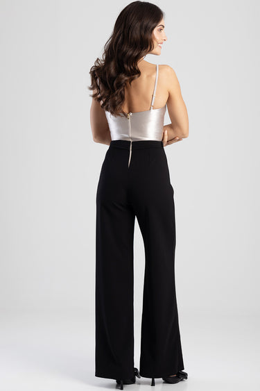 woman in a silver satin strap top with an open back paired with high waisted black wide leg pants seen from behind