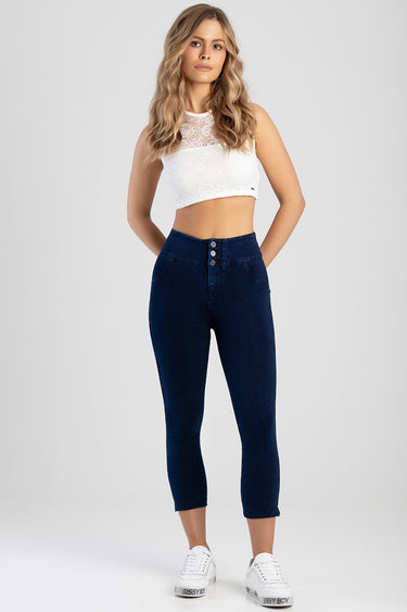 model wearing dark blue high waisted capri jeans with a white lace crop top and white sneakers