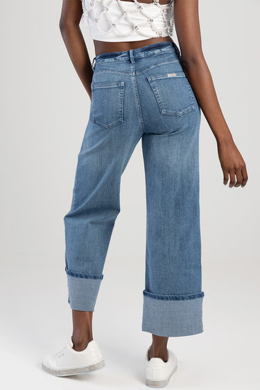 back view of a person in light blue wide leg jeans with cuffed hems and white sneakers
