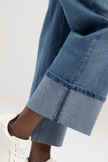 blue jean traders asher wide leg jeans on a model, close up of the cuff with lighter inside denim and white sneakers