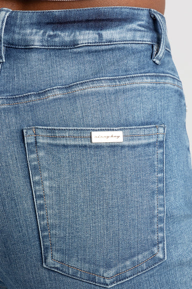 back view of blue jeans showing a back pocket with a small metal brand tag