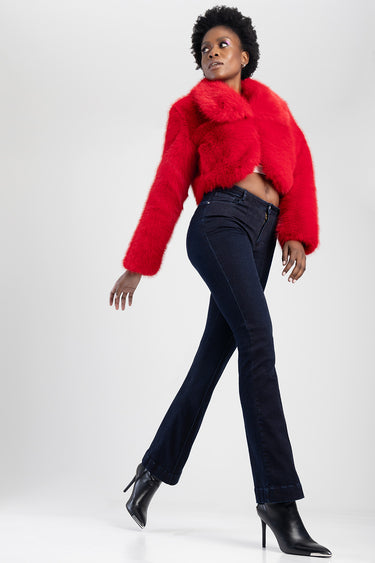 model wearing dark bootcut jeans by blue jean traders with a bright red cropped faux fur jacket and black heeled ankle boots