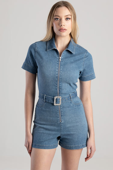 woman wearing light blue denim playsuit with front zip and decorative belt buckle
