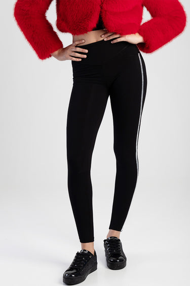 woman wearing black knit denim jeans with a silver side stripe, high waist, paired with black sneakers and a red textured