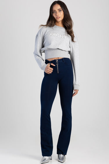 woman in navy high waist jeans with front zipper, paired with light grey cropped sweatshirt