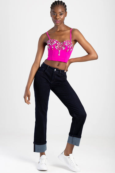 a woman in a hot pink embellished bustier top with rhinestones paired with dark straight leg jeans rolled at cuffs and