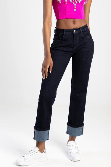 woman wearing dark indigo straight jeans with rolled cuffs, white sneakers and a bright pink top