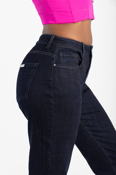 side view of a person wearing dark indigo jeans with back pocket and contrast stitching, paired with a bright pink cropped