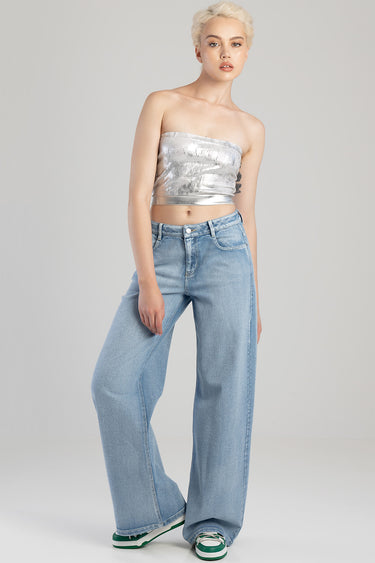 model wearing light blue wide leg jeans and a metallic silver bandeau top