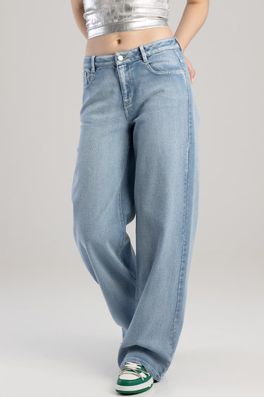 woman wearing light blue wide leg jeans with a high rise and front pockets, paired with a silver cropped top