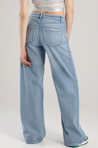 Blue Jean Traders wide leg jeans shown from behind on a model wearing a silver cropped top in a studio backdrop