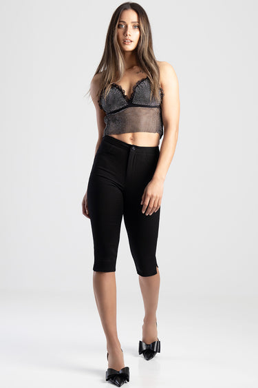 model wearing black denim capri trousers and a sheer black mesh top with lace trim