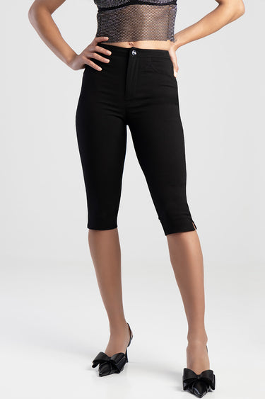 woman wearing black denim capri jeans with a mid rise and small hem slit